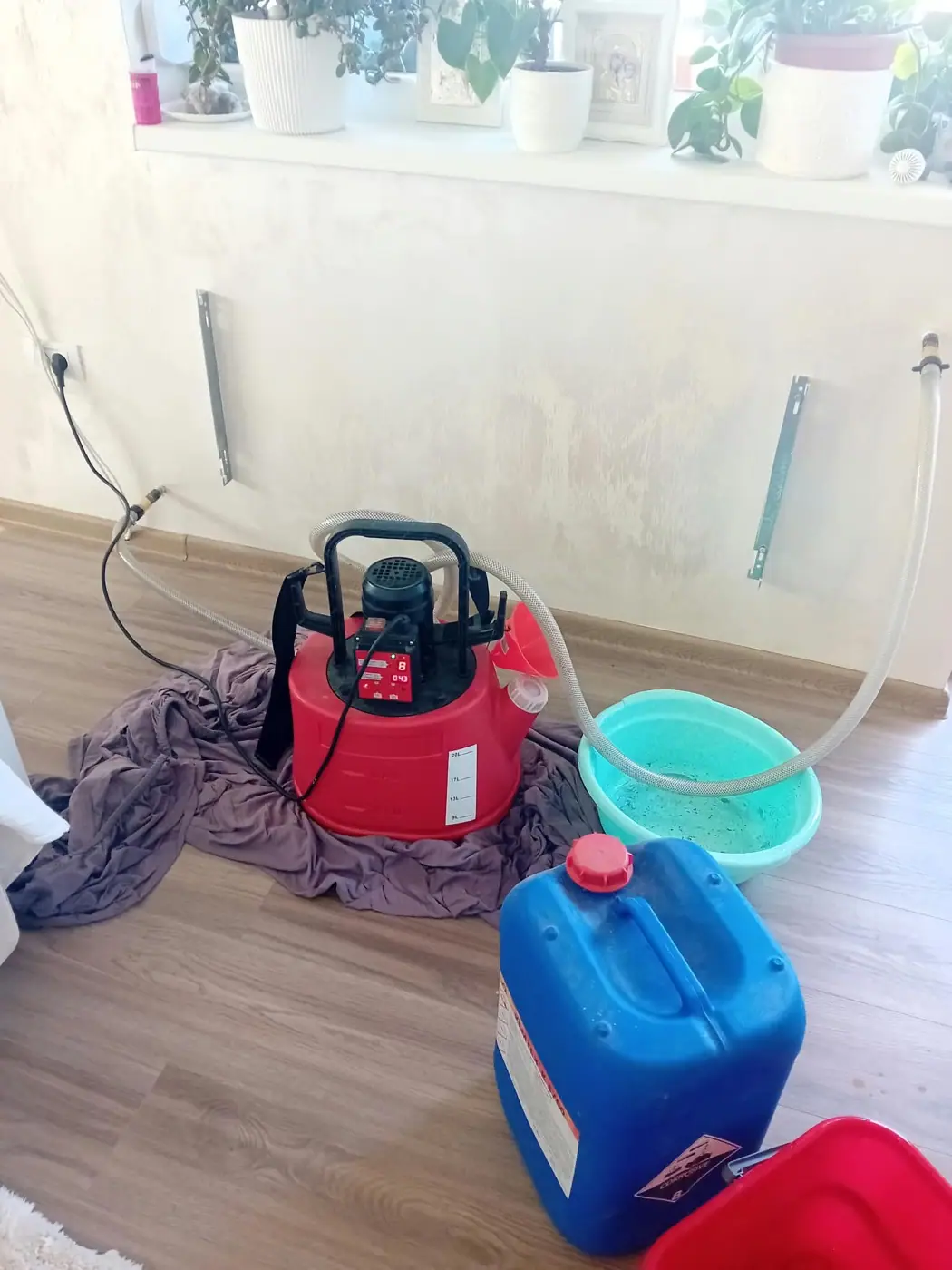 Pompă de spălare racordată la conductele caloriferelor demontate, într-o cameră de locuit